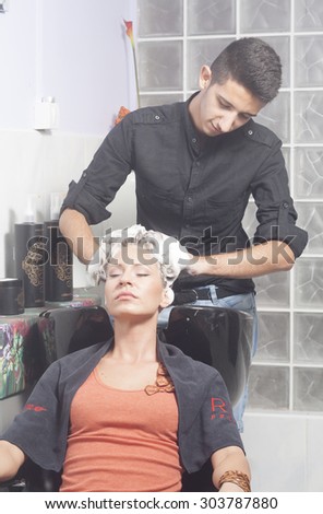 Hairdresser washing girls hair, shampoo foam.