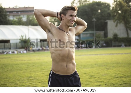Beautiful athlete smiling while stretching upper body, with strong abs.