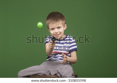 Cute blond kid, playing with plastic pistol. Green screen background.