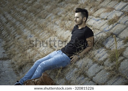 young man posing. rustic old stones.