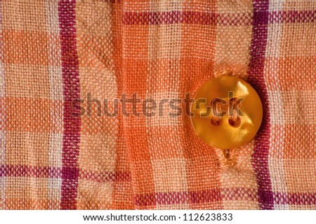 Close-up of orange squared shirt with button