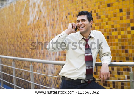 Businessman leaning against a railing and talking on a mobile phone