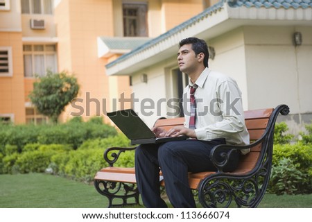 Businessman sitting on the bench and using a laptop