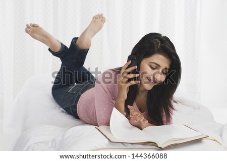 Woman talking on a mobile phone while reading a book