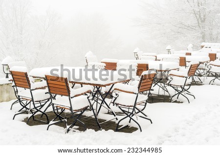 Scenery of tables and chairs covered in fresh snow during a winter