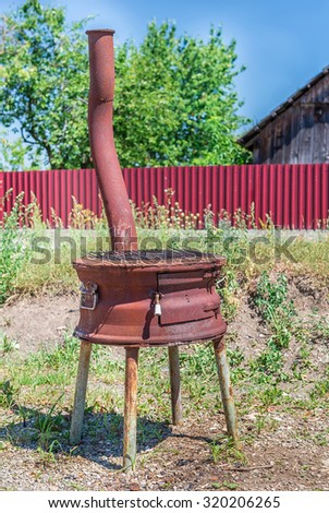 Rusty metal oven and grill in backyard in a sunny summer day ready for cooking