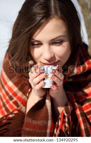 Girl drinks tea on a winter morning in a blanket