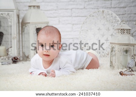 Little boy dressed in white laying on the white carpet