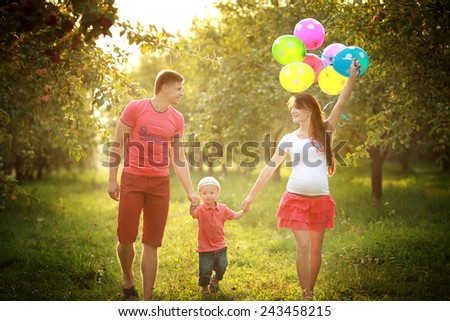 Young couple man and his pregnant wife and son with balloons