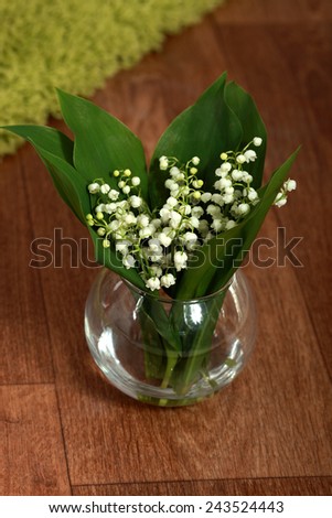 Beautiful lilies in glass vase on the wooden floor