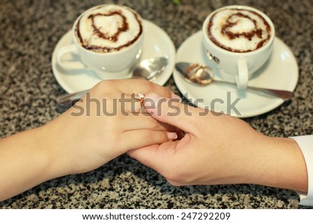 Couple\'s hands near two cups of coffee and wedding rings