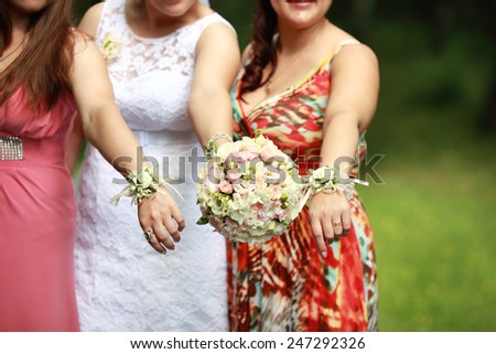 Bride\'s and her friends\' hands and wedding flowers