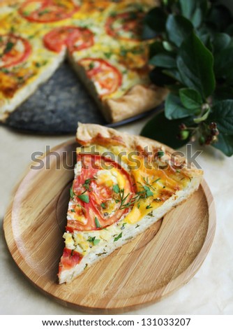 Slice of puff pastry snack pizza pie with cottage cheese, tomatoes and chopped fresh herbs on a wooden plate