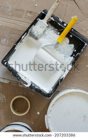 paint brush and paint roller with white paint