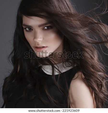 Portrait of a beautiful brunette girl with long hair in the studio