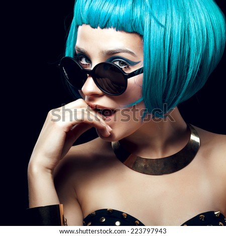 Portrait of beautiful girl with blue hair and yellow glasses, posing in studio