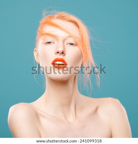 Portrait of beautiful young girl with orange hair on a blue background, closeup