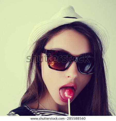beautiful cute brunette girl in the hat eating candy in the studio, lifestyle