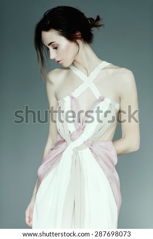 Portrait of a young beautiful girl in a light pink dress in the studio on a blue background