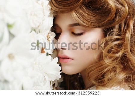 Beautiful girl with closed eyes on a background of white flowers, the concept of beauty and health