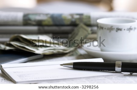 check with pen, coffee and money with newspapers on background