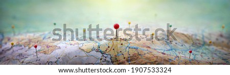 Pins on geographic map curved like mountains. Pinning a location on map with mountains. Adventure, discovery, navigation, geography, mountaineering, rock climbing, hike  and travel concept background.