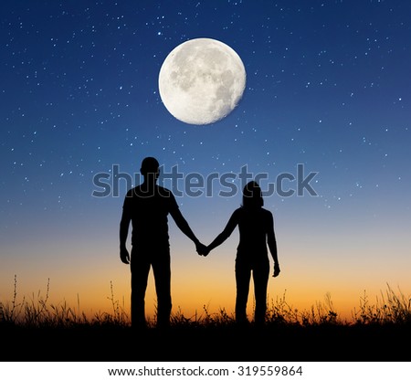 Silhouette of young couple under moon. The concept on the theme of love. Elements of this image furnished by NASA.