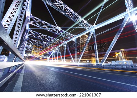 cars run fast through the colorful steel bridge with long tail at night