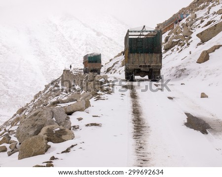 Ladakh,Jammu and Kashmir, India - April 10, 2012: Trucks running on the road on the mountains with snow falling in Ladakh, India