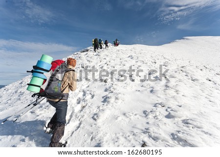 Group of hikers moving to the top in winter mountain.