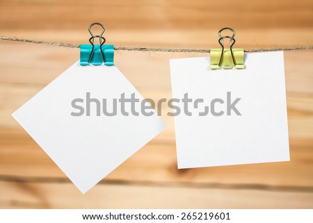 White paper cards hanging on a rope, on a wooden background.