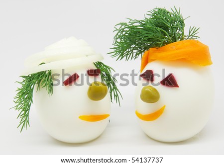 Two white eggs decorated with dill, onion and carrots on white background