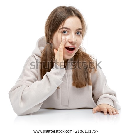 Pretty young teenager girl whispering a secret behind her hand. Teen woman telling news to her friends. Amazed lady says some wow Secret. Studio shot portrait. Isolated on white background. 商業照片 © 