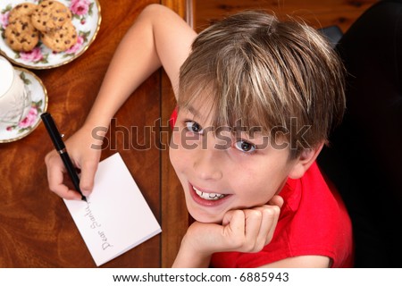 A child sitting at a desk writing a letter for Santa or Christmas card.