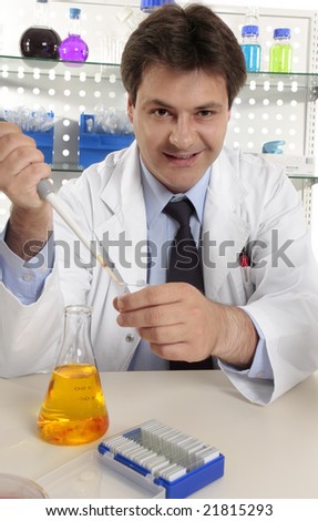 Scientist dispensing liquid from a pipette into a centrifuge tube.  He is looking up and smiling.