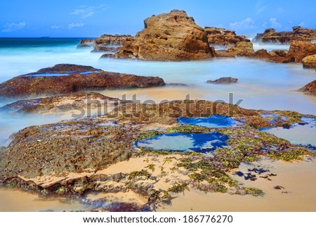 Long exposure of rocks and rock pools at low tide, motion in the water.