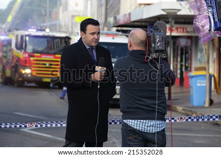 ROZELLE, AUSTRALIA - SEPTEMBER 4, 2014; News correspondent delivers a news bulletin on site of shop blast live to public television.