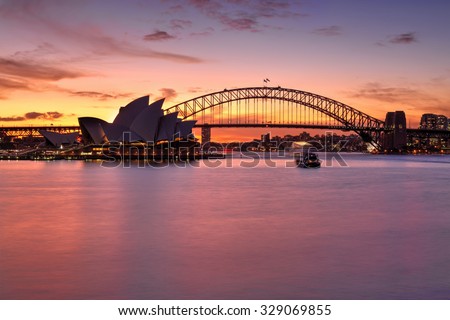 SYDNEY, AUSTRALIA - MAY 25, 2015; Rich vibrant sunset over Sydney with Sydney Harbour Bridge and Opera House also in view..  Boats on the harbour are in motion.