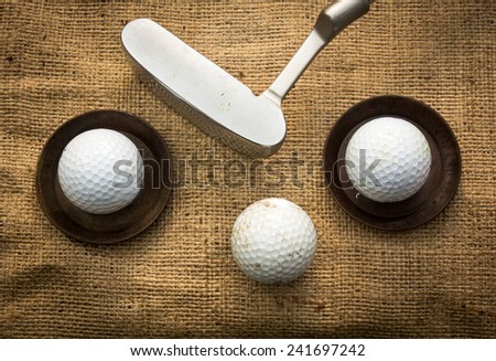 Golf balls lying on metal plates next to a putter