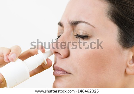 A young woman using nasal spray