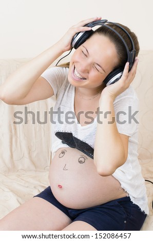 Pregnant woman relaxing with smiley face and headphones