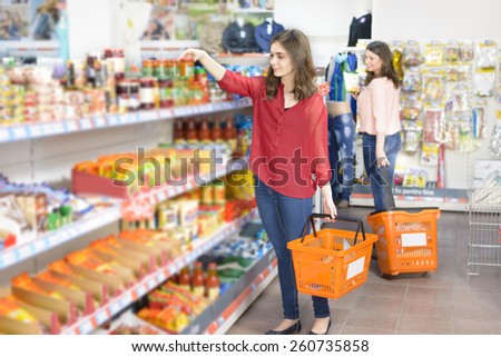 Happy woman with shopping basket choosing products in supermarket
