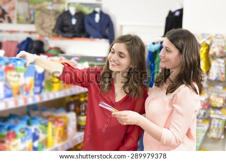 Happy woman with shopping basket choosing products in supermarket