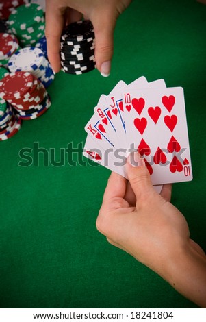 Cards with poker arrangement and female hand betting in the background.