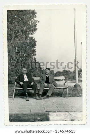 CENTRAL BULGARIA, BULGARIA,- CIRCA 1970: the area Plovdiv - Two middle-aged men, friends sitting on bench. Note: slight blurriness, better at smaller sizes - circa 1970