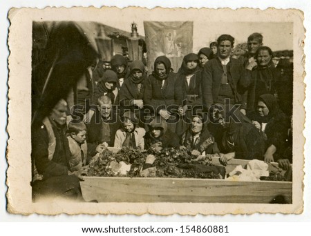 CENTRAL BULGARIA, BULGARIA - CIRCA 1950: Group of old women and a few old men weeping for the deceased in a coffin (village funeral) - Note: slight blurriness, better at smaller sizes - circa 1950