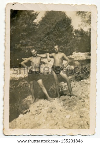 CENTRAL BULGARIA, BULGARIA - CIRCA 1945: Two young men posing in nature at mountain stream (dressed in lingerie) - Note: slight blurriness, better at smaller sizes - circa 1945