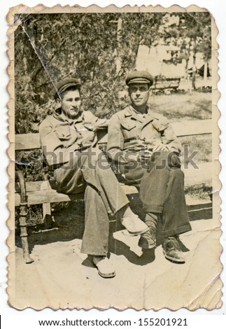 CENTRAL BULGARIA, BULGARIA - CIRCA 1940: Two young men in uniform sitting on a park bench - Note: slight blurriness, better at smaller sizes - circa 1940