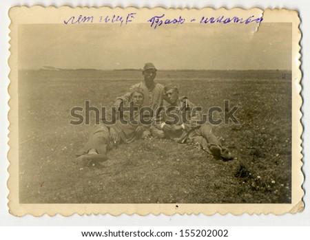 CENTRAL BULGARIA, BULGARIA - CIRCA 1945: Three young soldiers (friends) sitting on field - Note: slight blurriness, better at smaller sizes - circa 1945