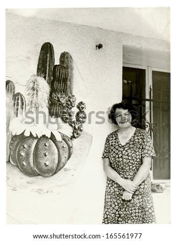 CENTRAL BULGARIA, BULGARIA - CIRCA 1975 - Older woman in front of her cacti (cacti are painting on the wall) - Note: slight blurriness, better at smaller sizes - circa 1975